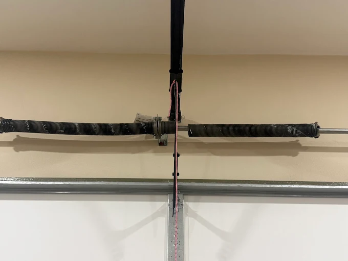 Broken torsion spring with a visible gap above a garage door