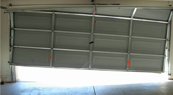 Off-track garage door hanging unevenly viewed from inside the garage